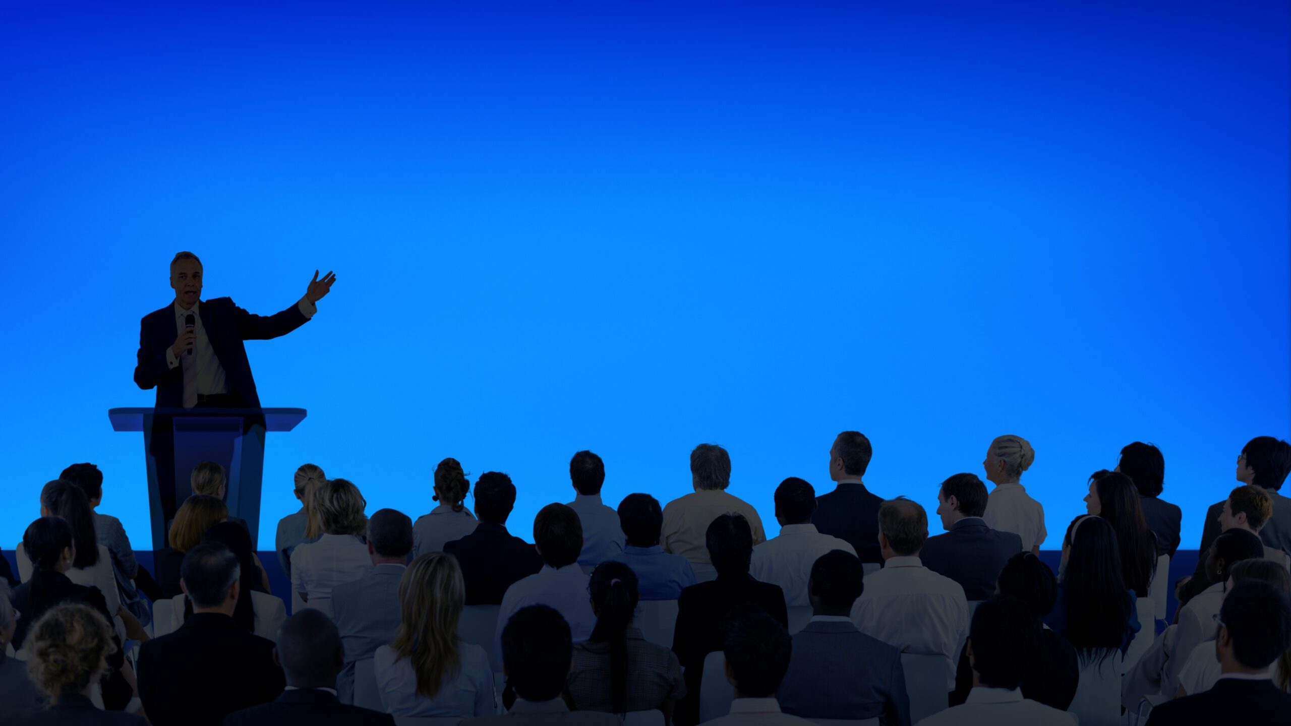Corporate businessman giving a presentation to a large audience Corporate businessman giving a presentation to a large audience