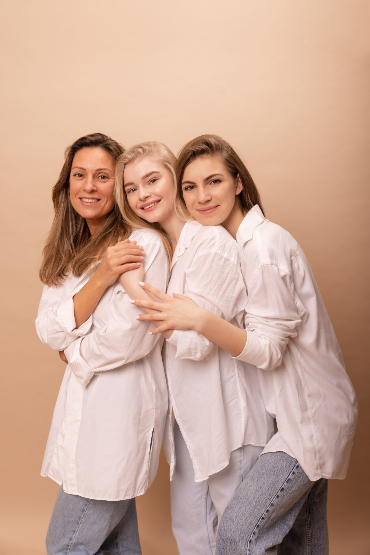 tres-mujeres-jovenes-piel-clara-camisas-blancas-sonrien-camara-abrazandose-si-contra-fondo-beige-concepto-belleza-femenina tres-mujeres-jovenes-piel-clara-camisas-blancas-sonrien-camara-abrazandose-si-contra-fondo-beige-concepto-belleza-femenina