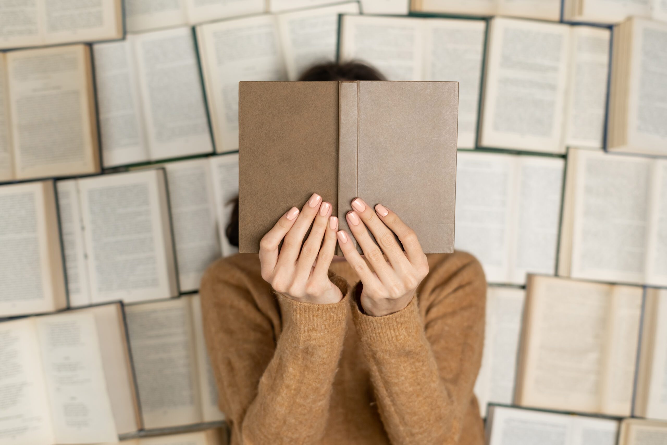 Top view, a girl in a cozy soft sweater lies on open books Top view, a girl in a cozy soft sweater lies on open books